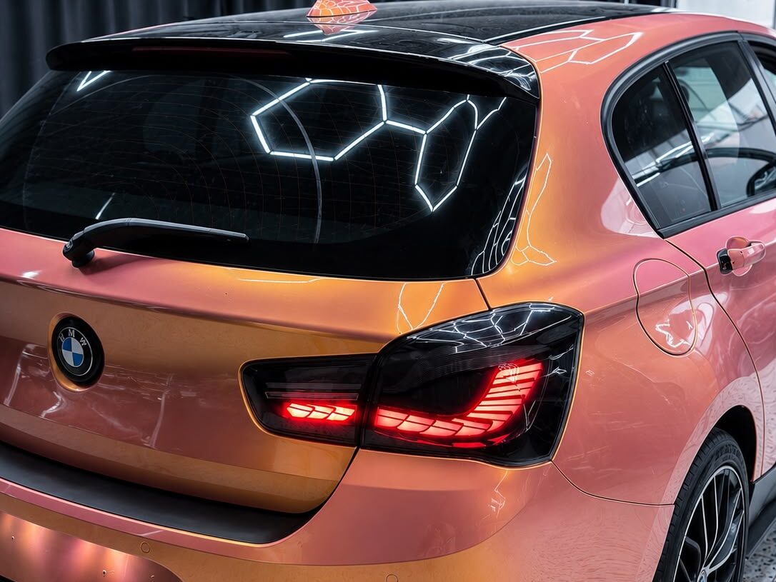 Vollfolierter BMW 1er in changierendem Orange-Rosé, Heckansicht im Glanzgenie-Studio